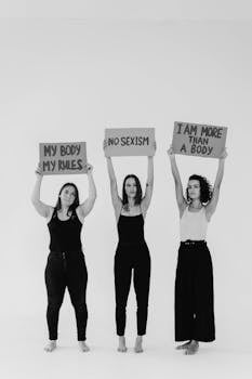 Three women hold powerful feminist slogans advocating for gender equality.