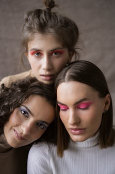 Stylish portrait of three women with vibrant eye shadow posing in a studio setting.