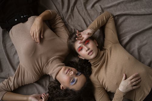 Women in Brown Turtle Neck Long Sleeves Lying on the Fabric while Looking at the Camera