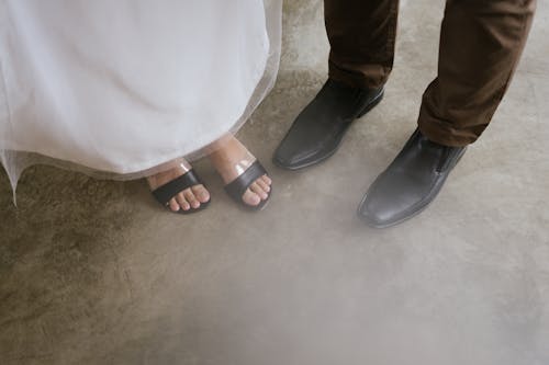 People in Black Sandals and Black Leather Shoes Standing on the Floor