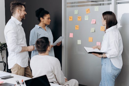 Diverse team collaborating in an office, discussing ideas using sticky notes and notepads.