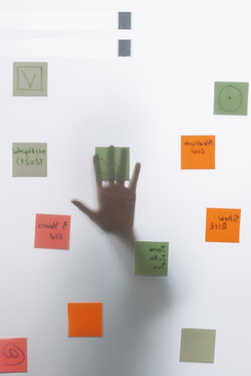 A Hand on Glass Wall with Sticky Notes