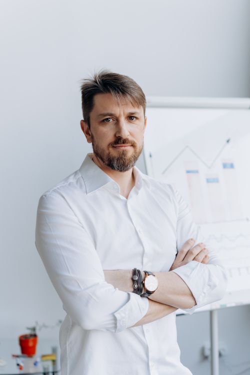 Free Confident businessman in white shirt posing in front of office chart. Stock Photo