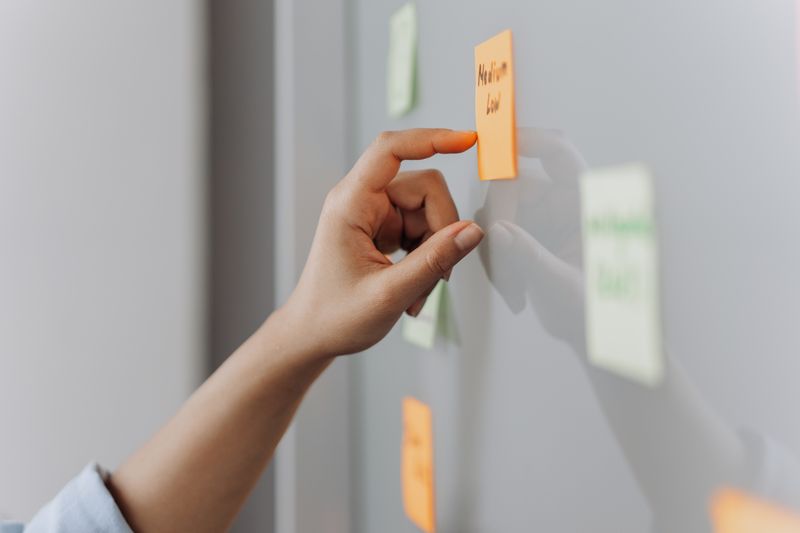 hand peeling a sticky note off a desk