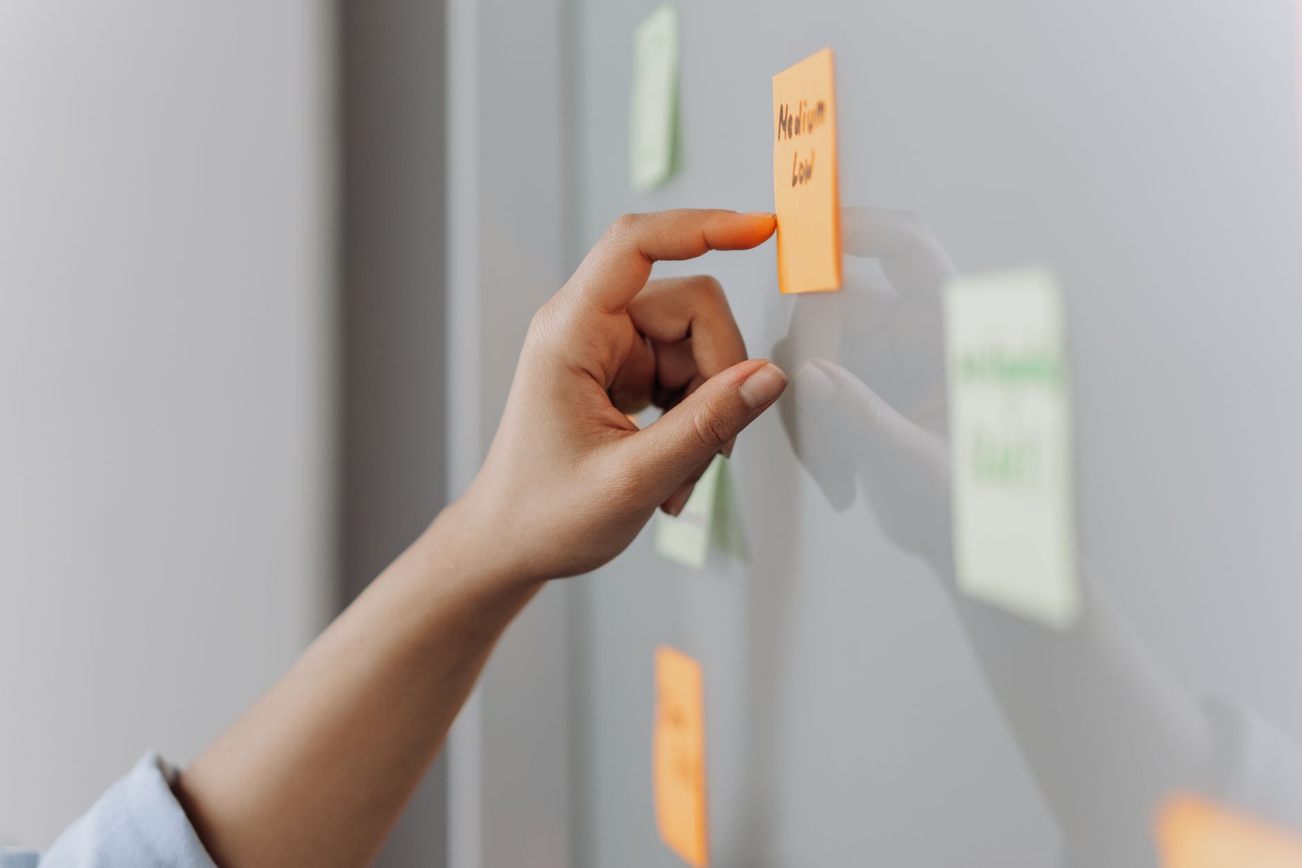 Index Coverage GSC - A hand placing a sticky note on a reflective surface in an office setting.