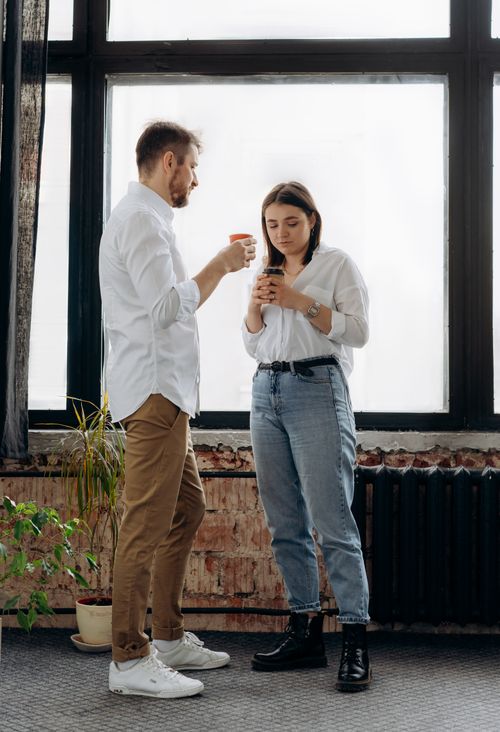 Free A man and woman enjoying a coffee break inside an office, engaging in conversation. Stock Photo