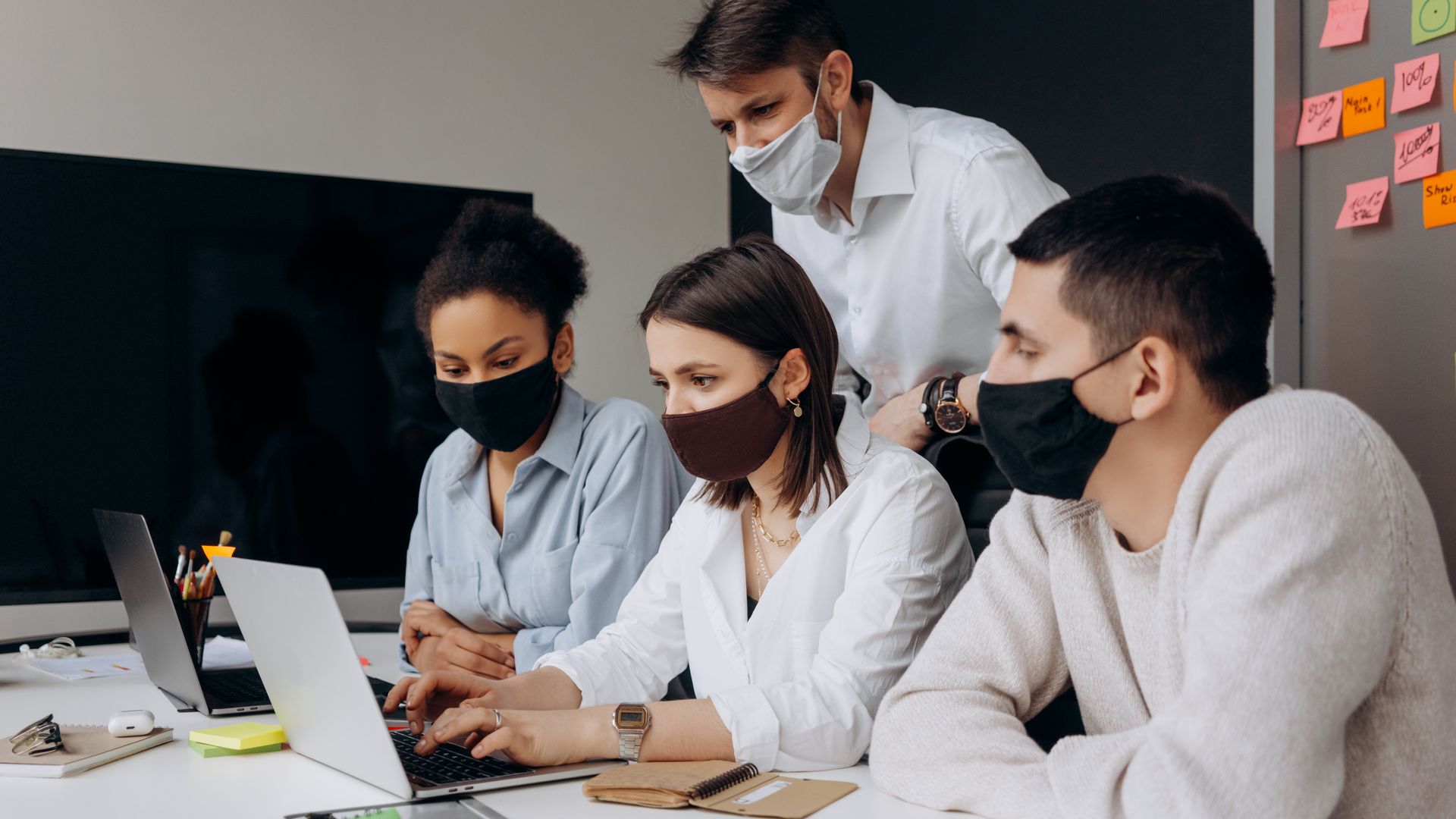 A diverse team working together in an office, showcasing safety measures with face masks.