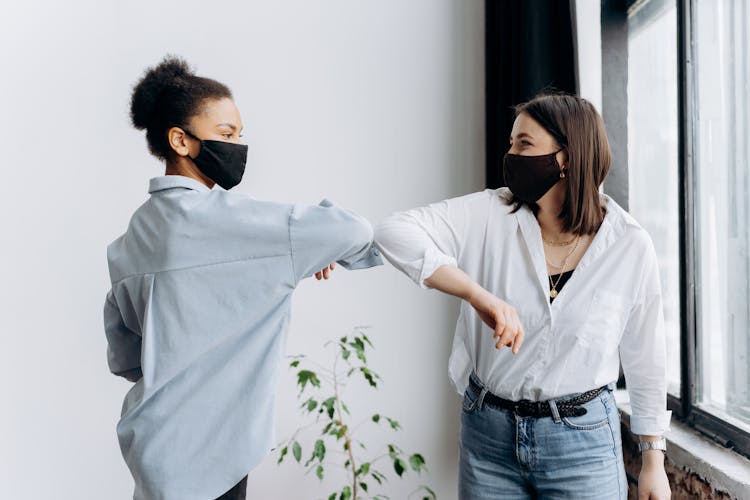 Two Women Wearing Face Mask Elbow Bumping