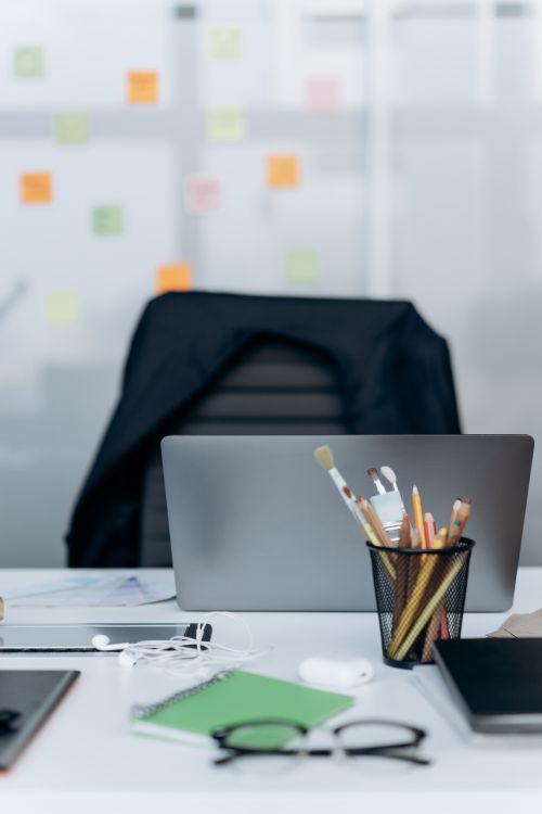Free Stylish office desk with a laptop, stationery, and notes on glass wall. Stock Photo