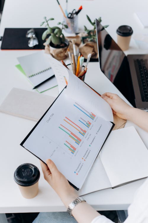 Free A Hand Holding a Clipboard with Printed Graph Stock Photo