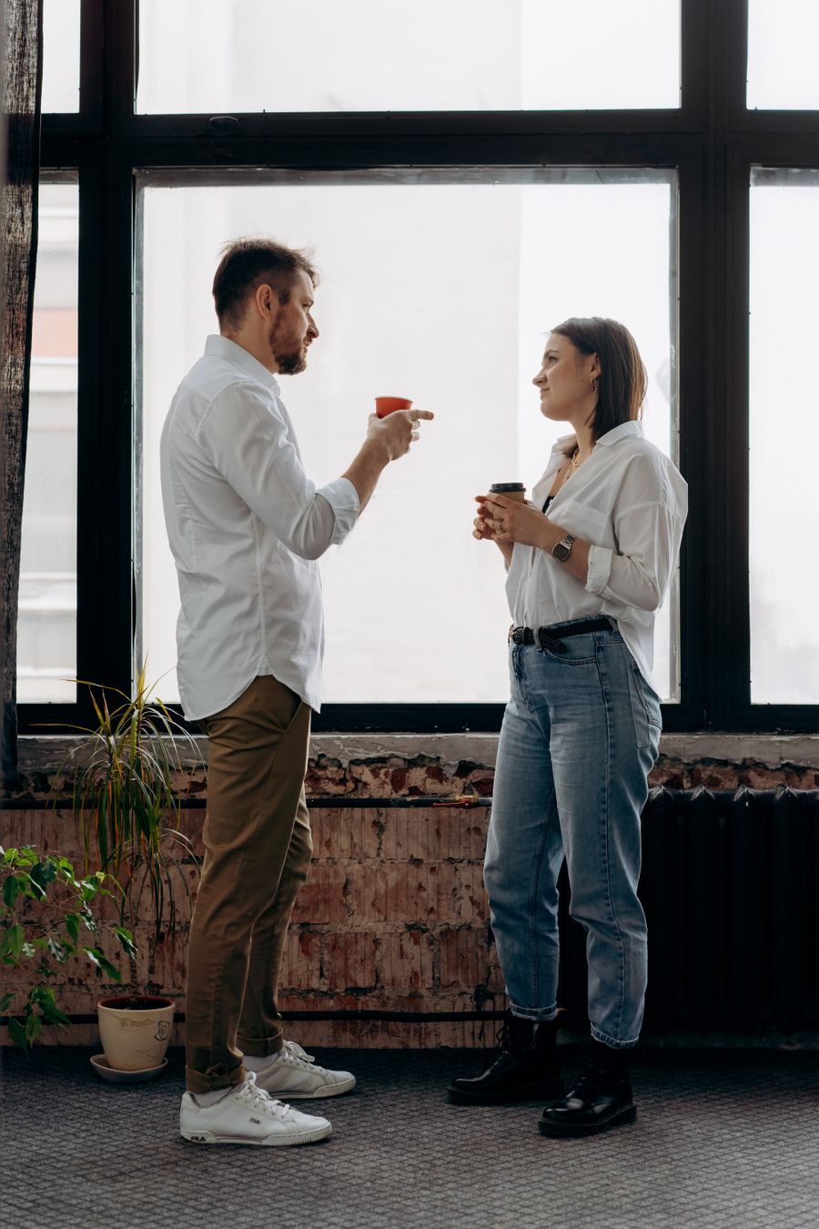 Two colleagues talking over coffee in a bright office — photo by Mikhail Nilov on Pexels
