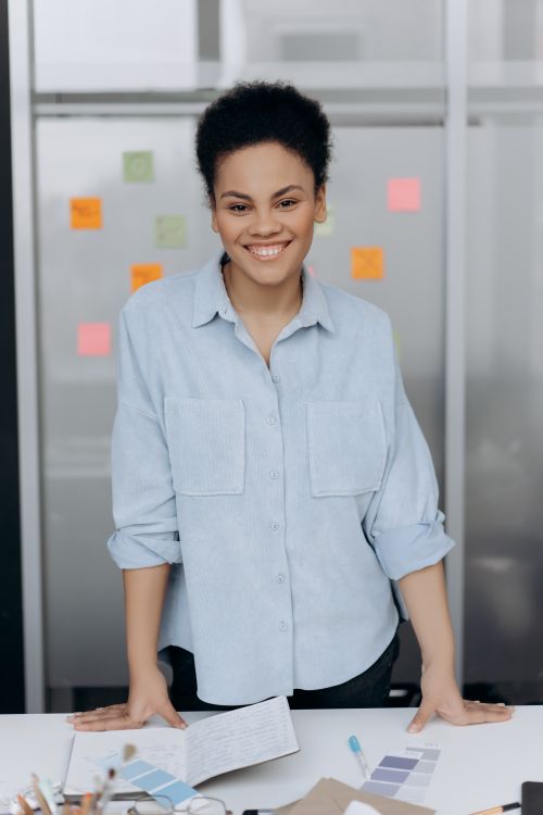Free Confident businesswoman smiling at her desk in a modern office with notes behind. Stock Photo