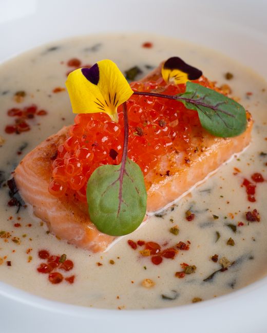 A delectable salmon dish topped with roe and garnished with edible flowers, perfect for seafood lovers.