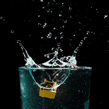 Close-up of a water splash in a glass against a black background, capturing motion.