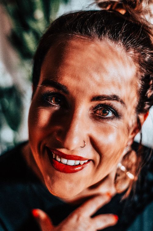 Free Close-up portrait of a happy woman with red lips and nose piercing, smiling warmly. Stock Photo