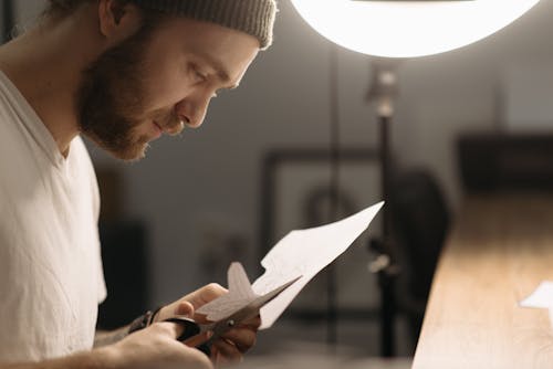 Man Cutting White Paper With Scissors 