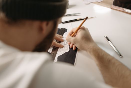 Tattoo artist drawing intricate design in tattoo parlor, showcasing creativity and precision.