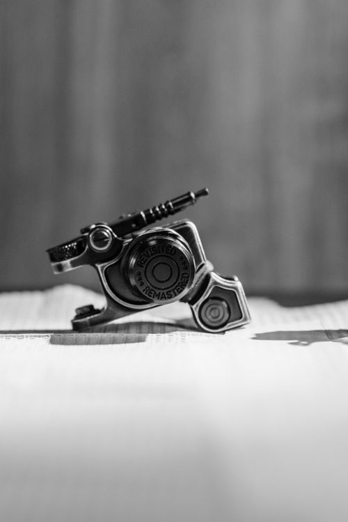 Free Monochrome close-up of a detailed tattoo machine part on a textured surface. Stock Photo