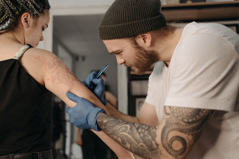 Tattoo artist applying a stencil during a first tattoo appointment consultation Tattoo artist applying a stencil during a first tattoo appointment consultation