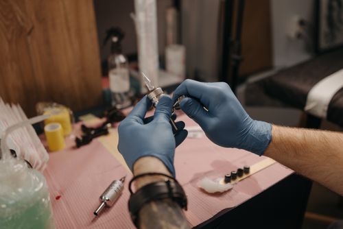 Free Professional tattoo artist setting up machine and ink in a tattoo parlor. Stock Photo
