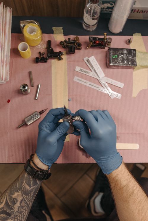 Free Overhead view of a tattoo artist setting up a tattoo machine on a table. Stock Photo
