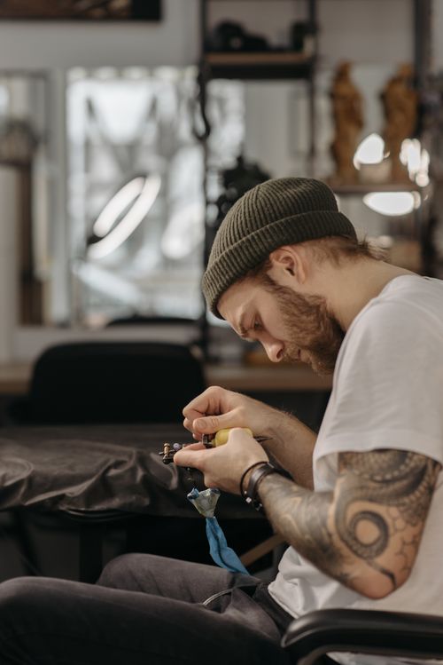 Free A focused tattoo artist perfects a tattoo design inside a contemporary studio. Stock Photo