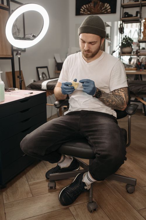 Free Tattoo artist sitting in studio preparing tools with a ring light. Stock Photo