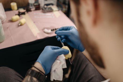 Close-up of a tattoo artist setting up a tattoo machine in a studio setting with precision.