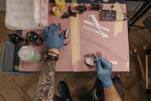 Free Tattoo artist's hands preparing machines and ink in a tattoo parlor setting. Stock Photo