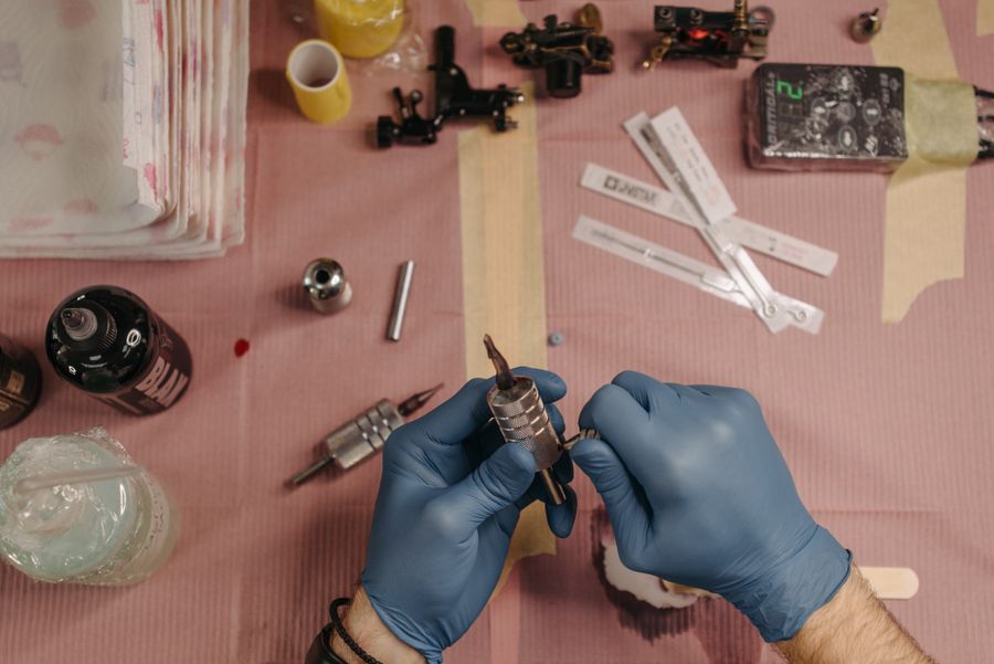 Tattoo tools and pigment cups laid out on a pink cloth