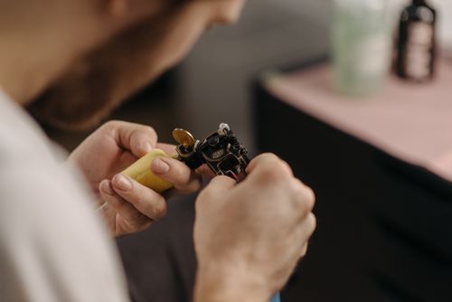 Free Close-up of a tattoo artist adjusting a tattoo machine in a studio setting. Stock Photo