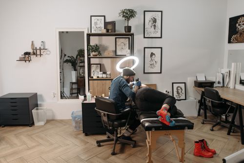 Free Tattoo artist using a tattoo machine in a stylish studio, focusing on intricate design. Stock Photo