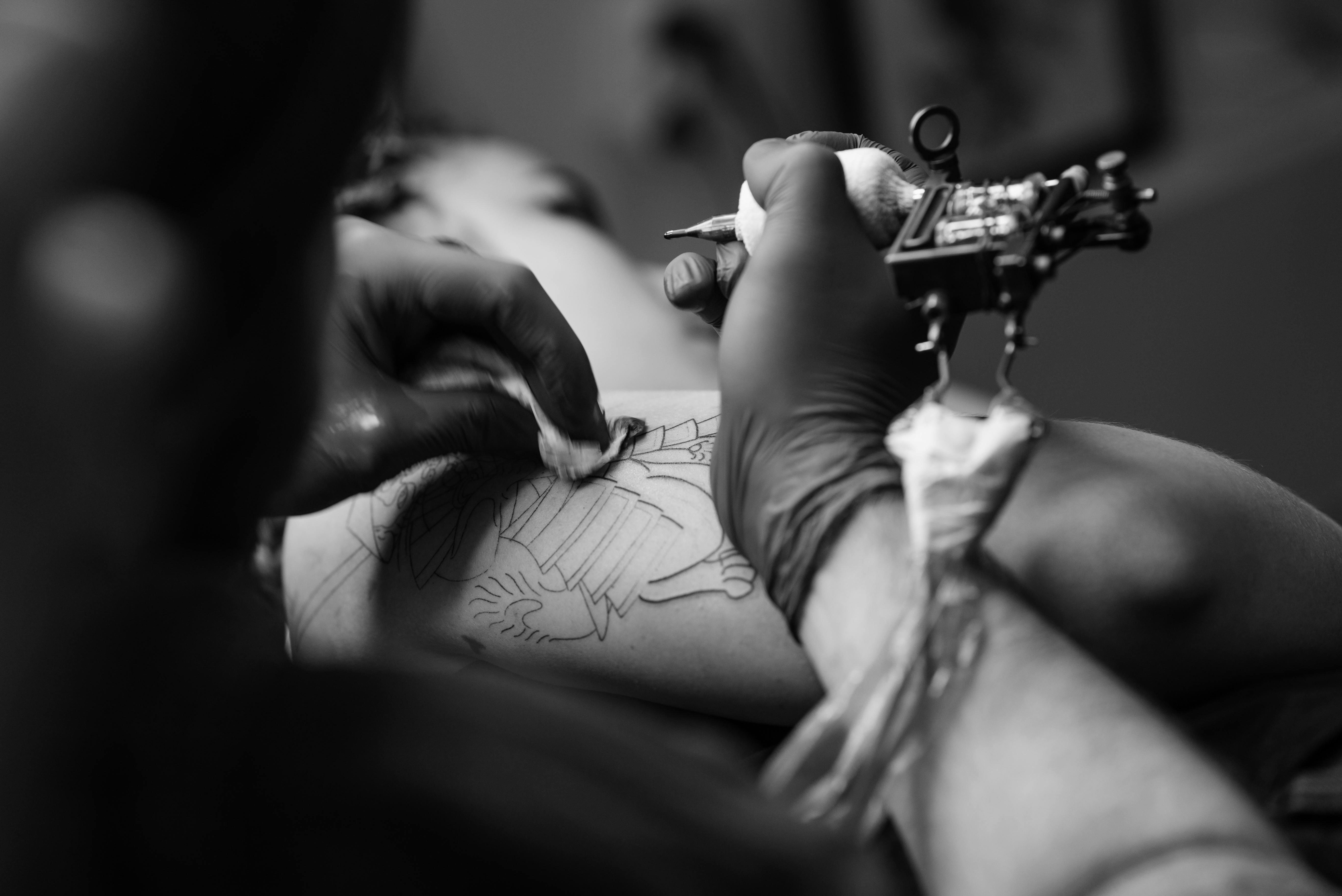 Man Holding Tattoo Machine And Tattooing Person Arm  Free Stock Photo