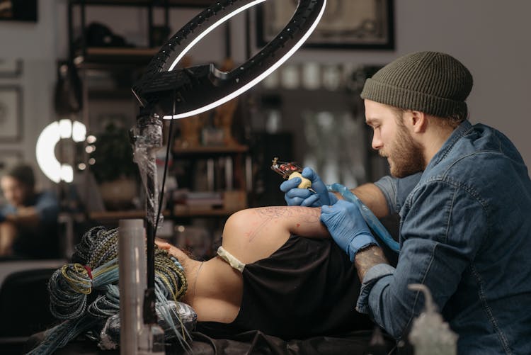 Man Tattooing A Client's Arm