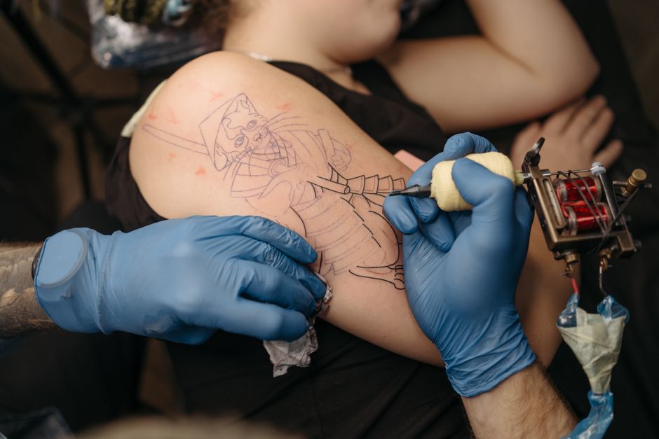 Tattoo apprentice practicing steady line control to reduce tattoo outline pain during a session Tattoo apprentice practicing steady line control to reduce tattoo outline pain during a session