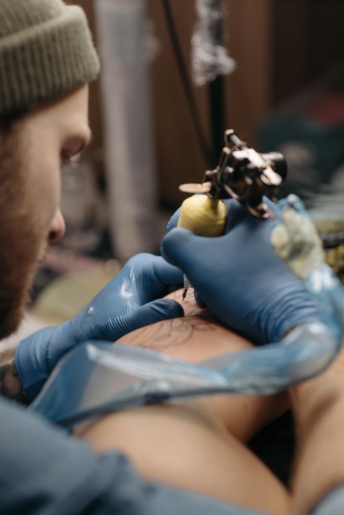Free Close-up of a tattoo artist working on a tattoo design in a studio setting. Stock Photo