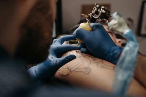 Free Detailed image of a tattoo artist creating intricate skin art with a tattoo machine. Stock Photo