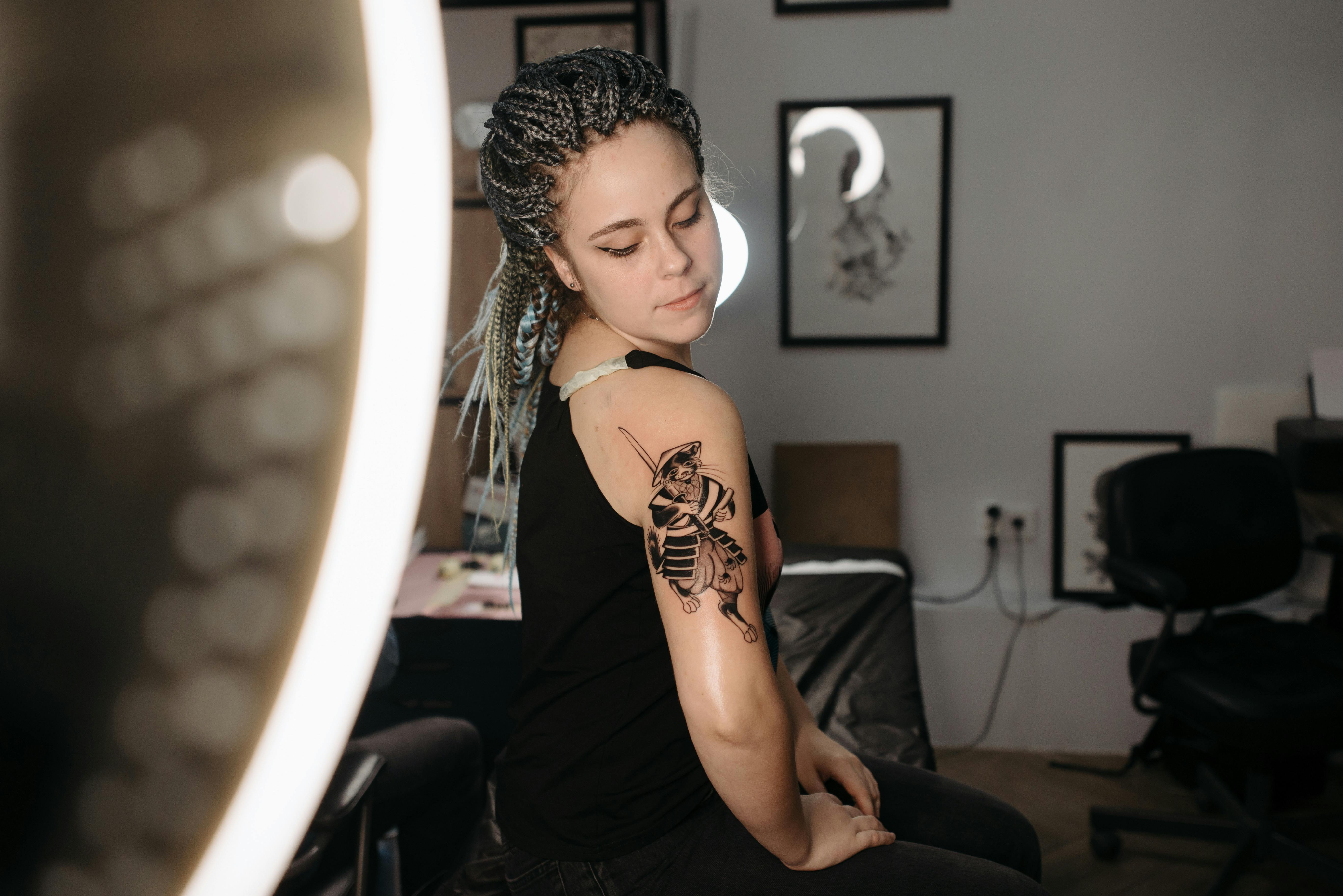 Woman with arm tattoo in a studio under professional lighting, showcasing art.