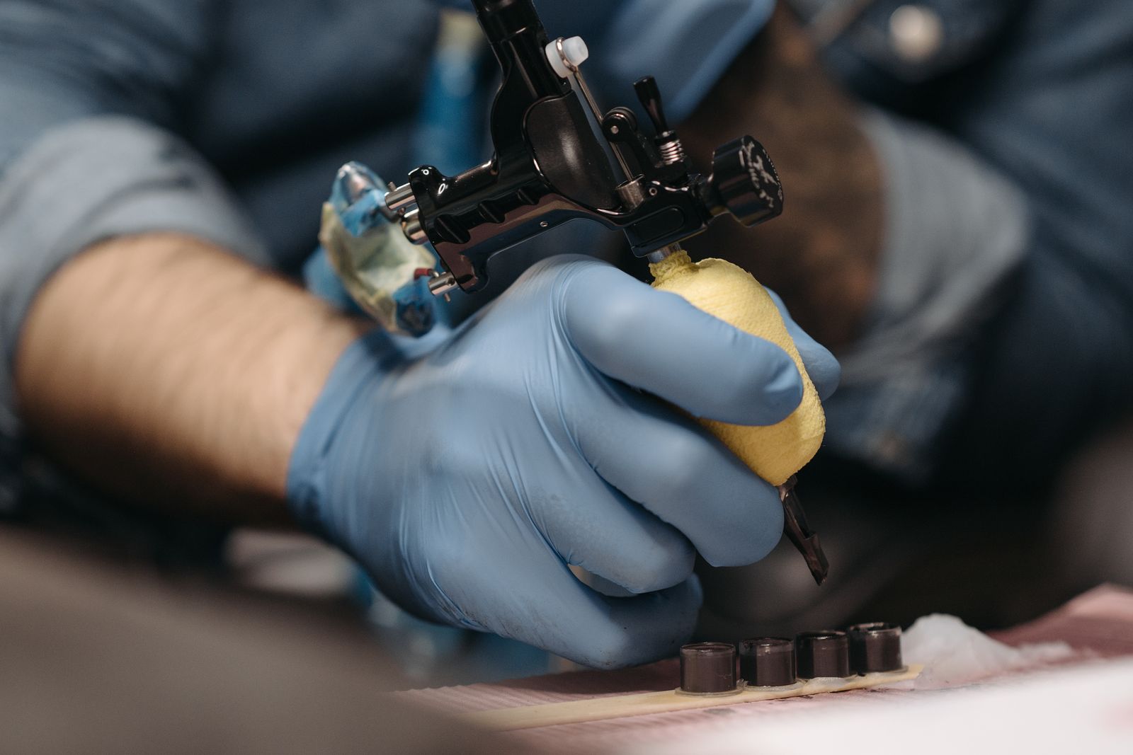 An artist finishing a fresh tattoo on a client's arm.