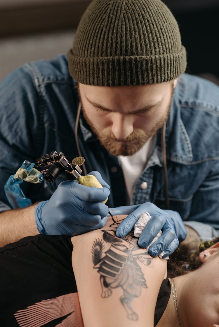 Man Drawing A Tattoo On The Woman's Elbow