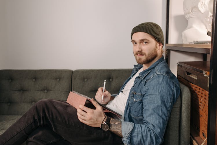 Man In Denim Jacket And Beanie Hat Sitting On A Couch