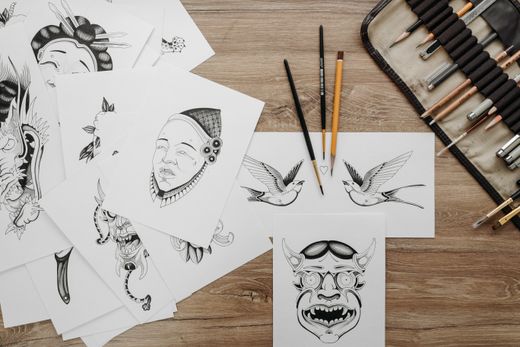 Ink sketches and drawing tools laid out on a wooden table — photo by Pavel Danilyuk on Pexels