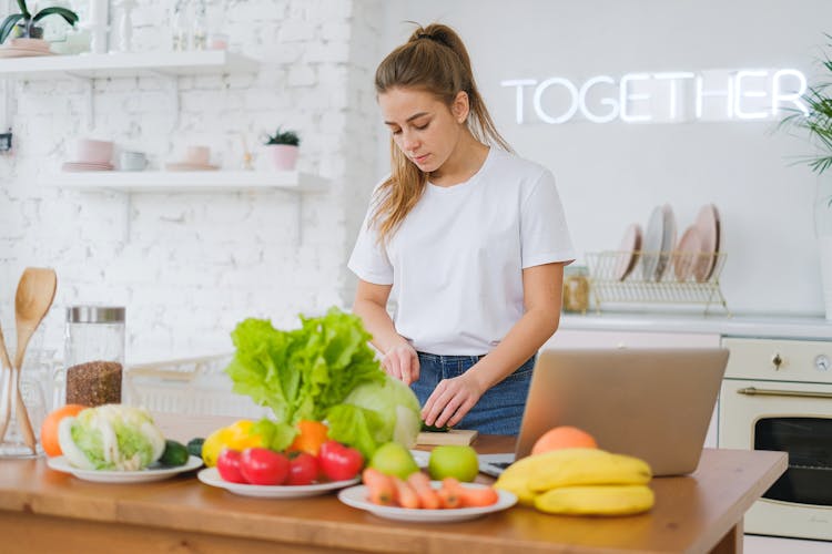 Woman Standing At Table With Vegetables