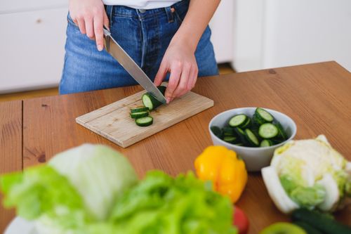 Free Healthy food preparation with fresh cucumbers and vegetables on a wooden table. Stock Photo