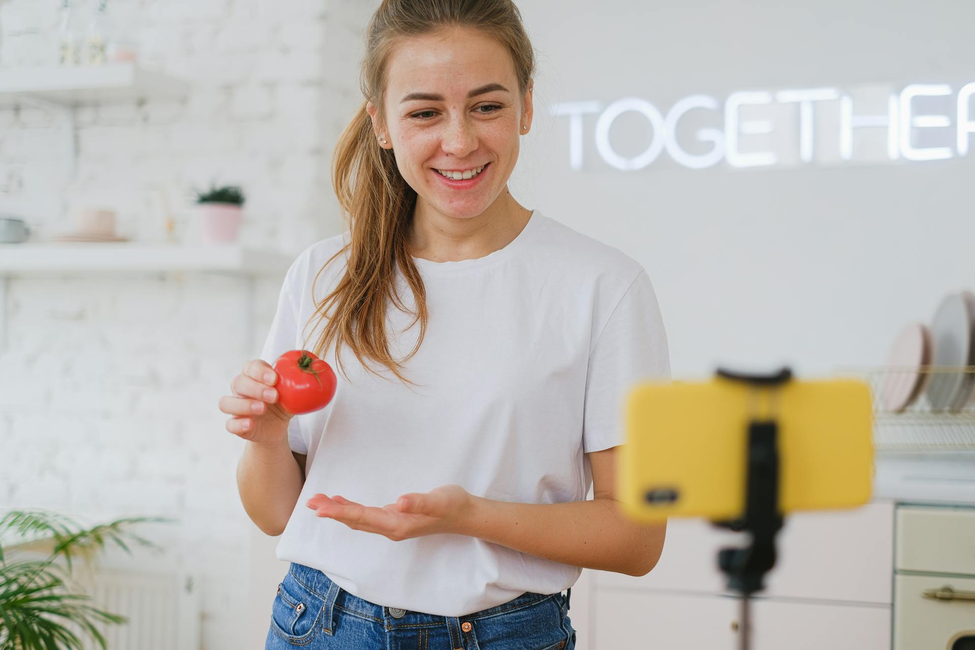 Woman Holding a Tomato and Live Streaming with her Smart Phone