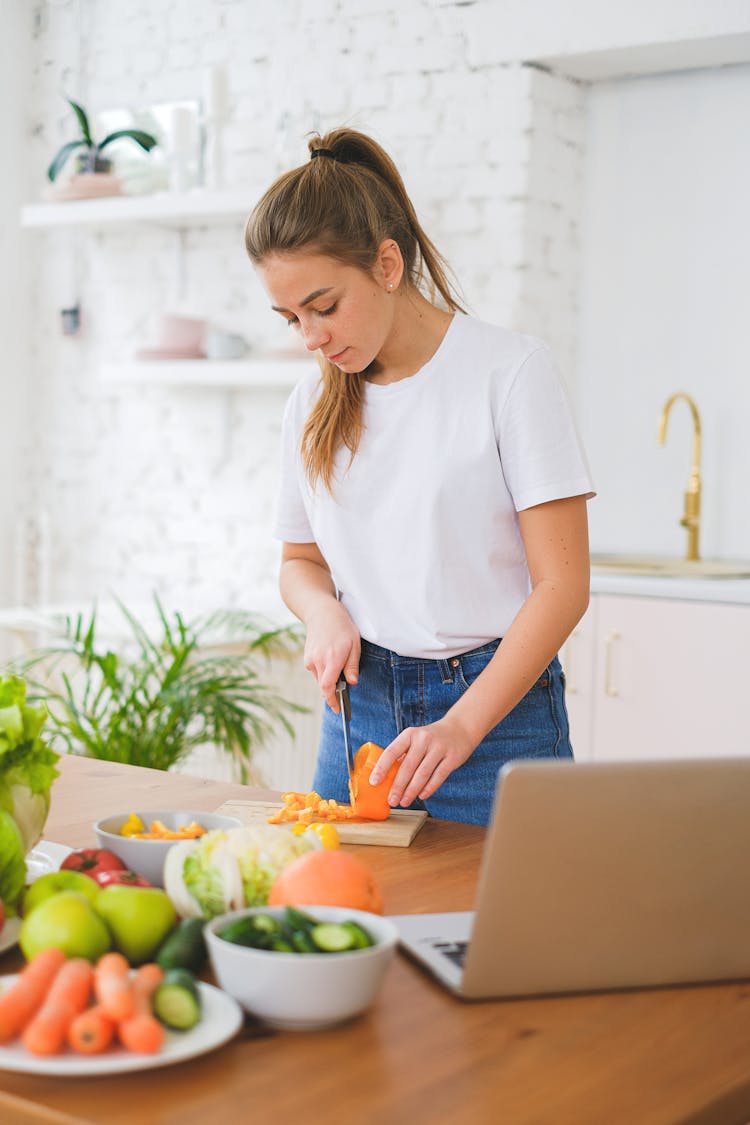 Woman Slicing A Vegetable On Chopping Board