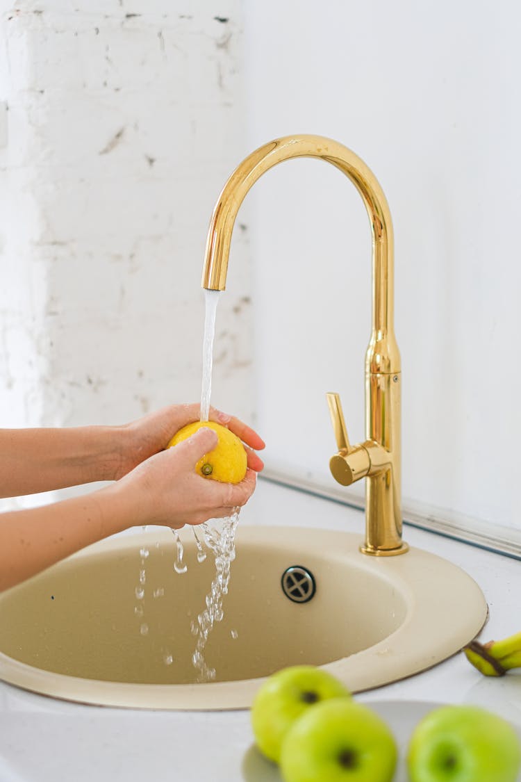 Person Washing A Fresh Lemon On Sink