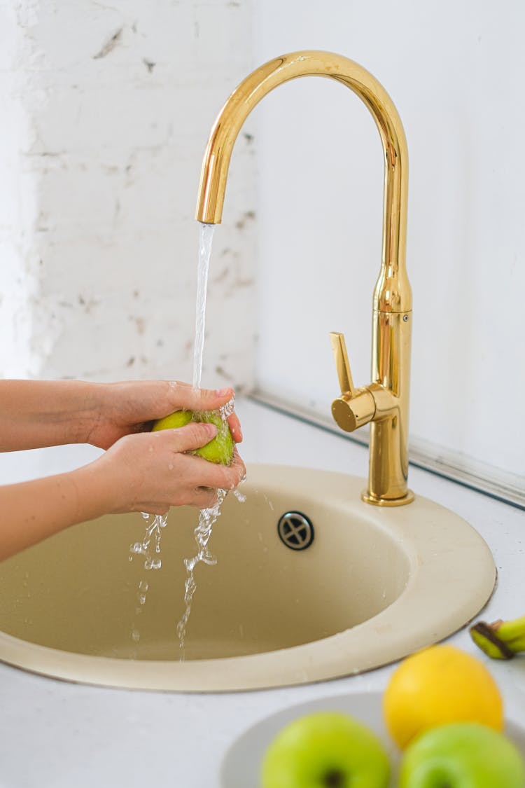 Person Washing A Green Fruit On Her Hand