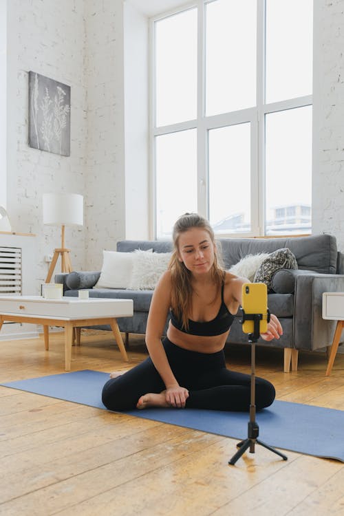 Woman Sitting on a Yoga Mat Using a Cellphone