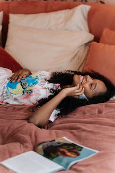 Adolescent girl enjoying conversation while lying on bed with a phone.